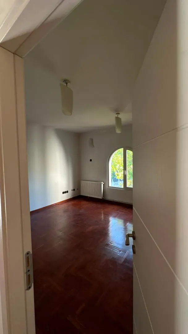View of an empty room with parquet flooring through an open door.