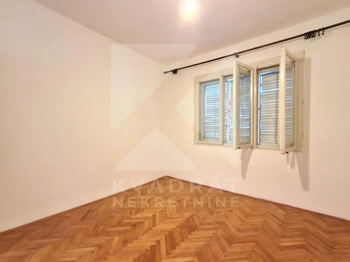 Empty room with parquet flooring and an open window.