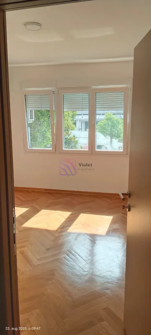 Empty room with hardwood flooring and three windows.
