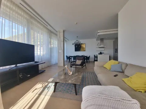 Spacious living room with a sofa, large TV, and dining area in the background. - image 9