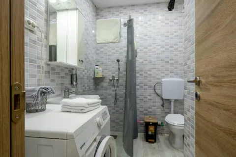 Smaller bathroom with a shower cabin, sink, and washing machine. - image 7