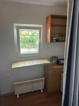 Manja kuhinja sa drvenim elementima, prozorem i radnim stolom. - image 3