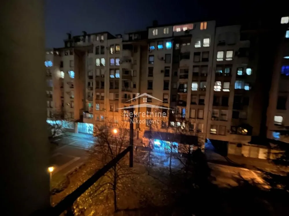 Noćni pogled sa prozora na okolne zgrade i ulicu.