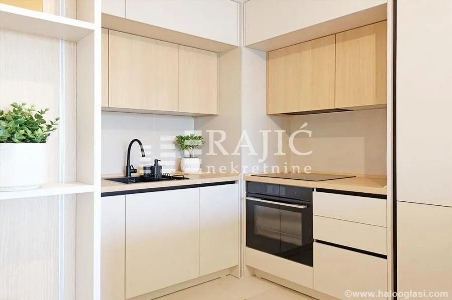 Modern kitchen with white units, wooden upper cabinets, and a built-in oven.