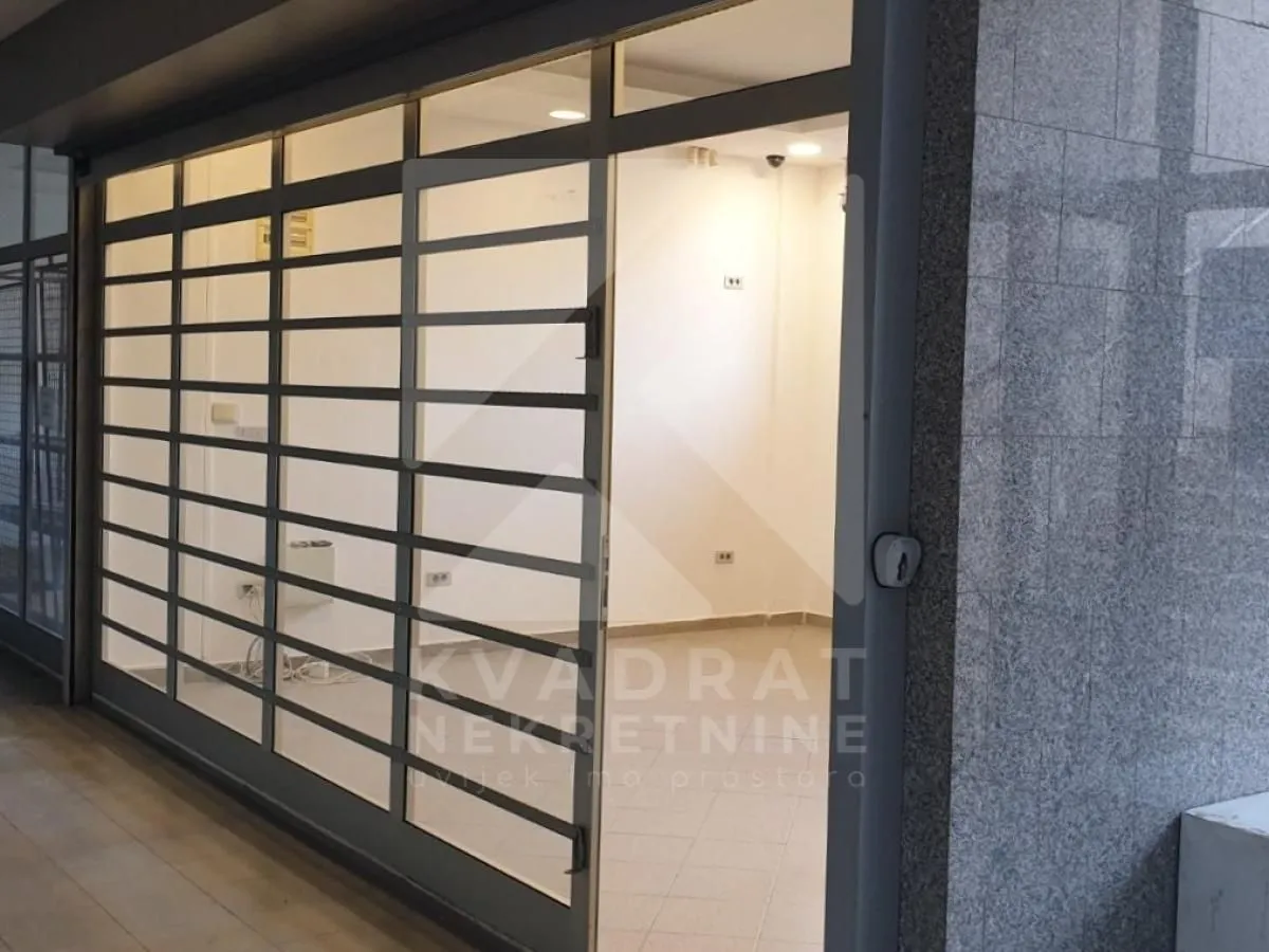 Entrance to a commercial space with security shutters and a glass storefront.