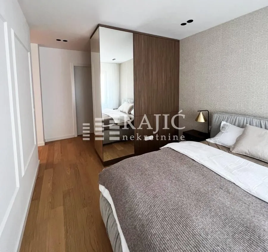 Modern bedroom with a double bed and a built-in wardrobe with a mirror.