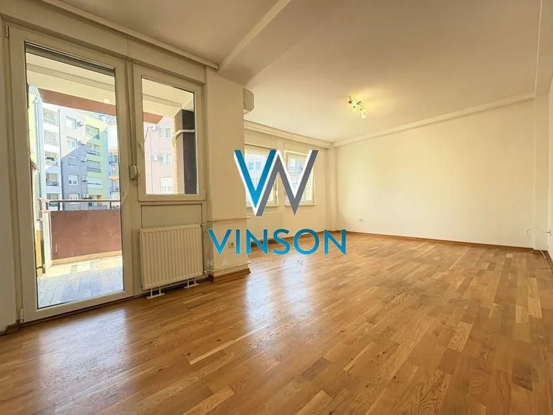 Empty living room with wooden flooring and access to the terrace.