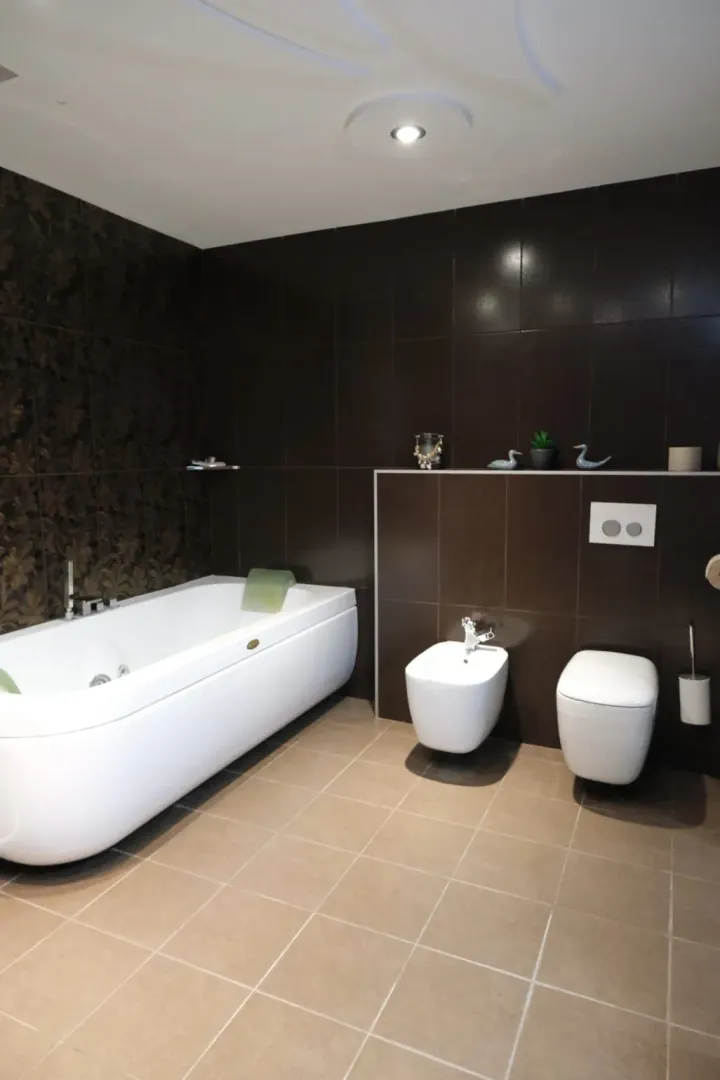 Spacious bathroom with a white bathtub, bidet, and toilet in a modern style.