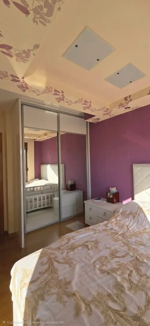 Spavaća soba sa bračnim krevetom, garderoberom sa ogledalom i ljubičastim zidom.