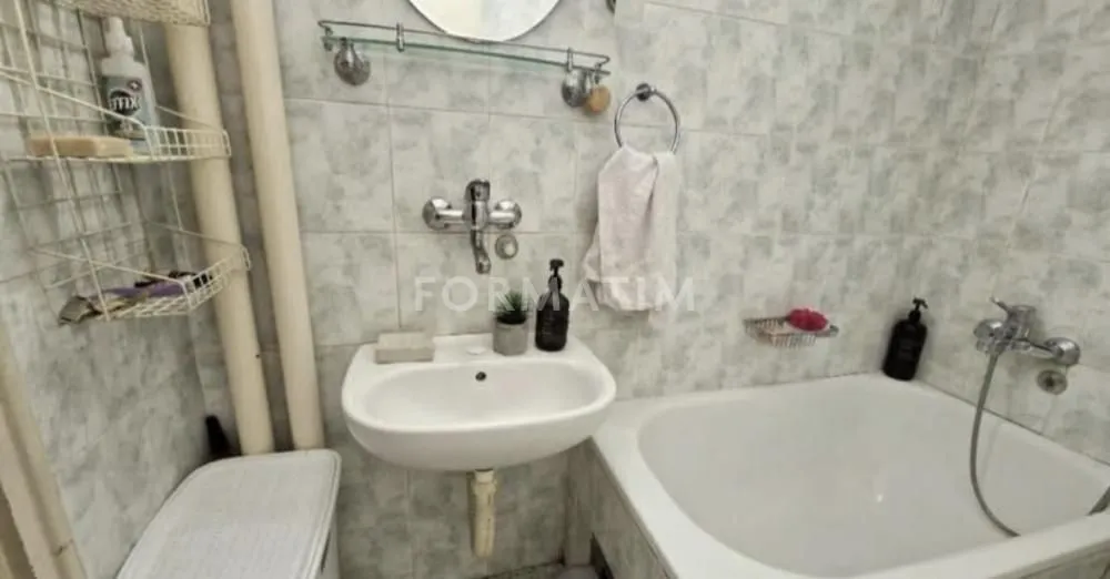 Manje kupatilo sa umivaonikom, kadom i policama za odlaganje.