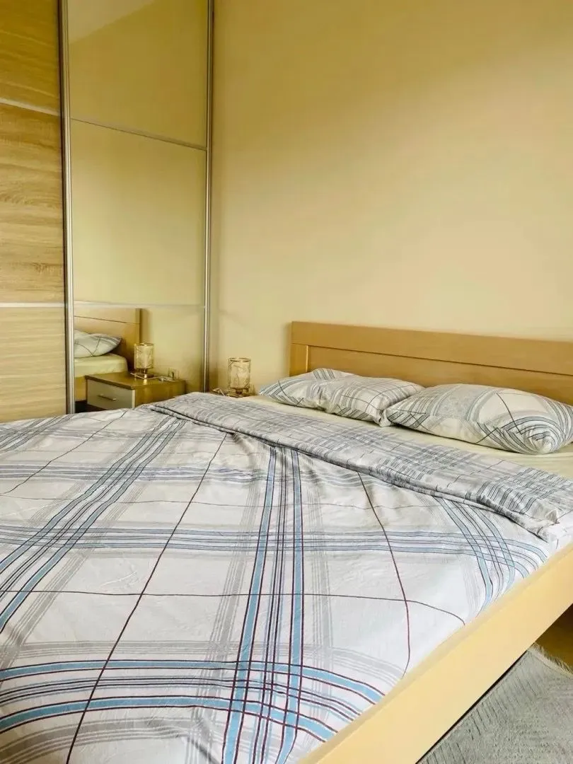 Furnished bedroom with a double bed and a mirrored built-in wardrobe.