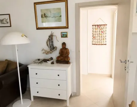 Pogled na dio dnevne sobe sa bijelom komodom, lampom i dekorativnim slikama na zidu. - image 8