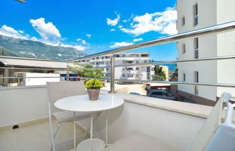Bright balcony with a table, chairs, and a view of surrounding buildings and mountains. - image 7