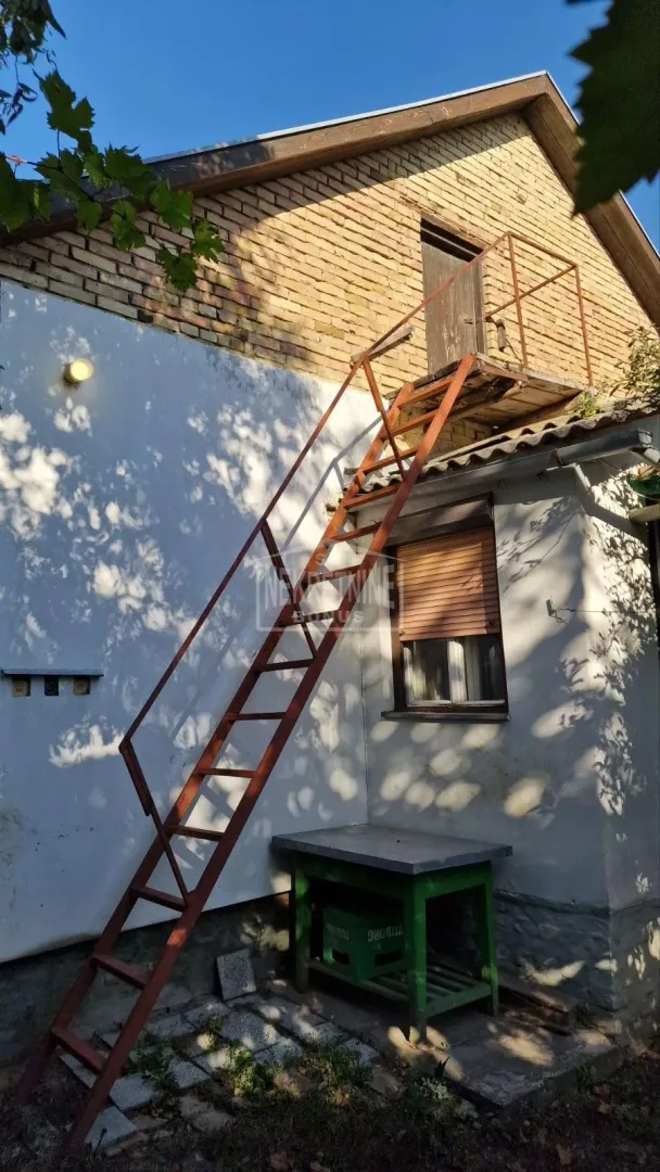 Spoljni pogled na kuću sa metalnim stepenicama koje vode na sprat.