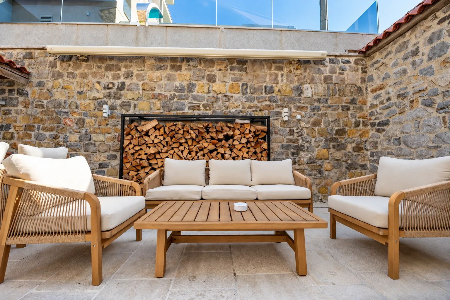 Terrace with seating furniture and a stone wall.