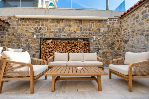 Terrace with seating furniture and a stone wall. - image 17