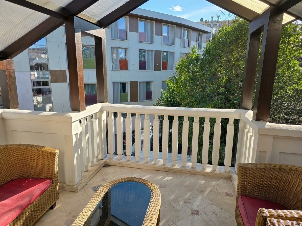 Covered balcony with seating furniture and a view of the building.