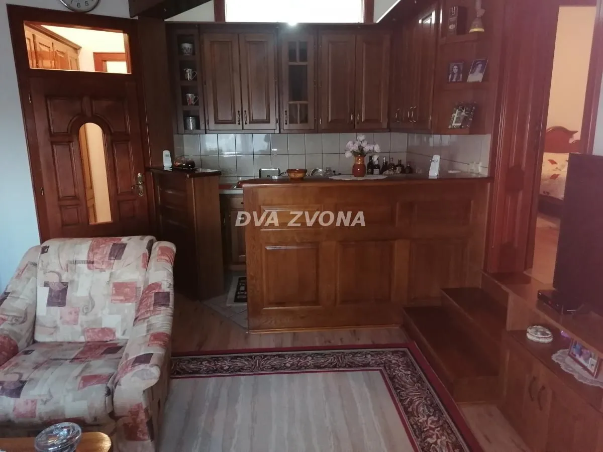 Living room with wooden kitchen elements and an armchair.