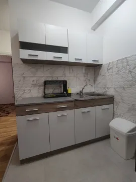 A small modern kitchen with white and wood-accented cabinets. - image 6