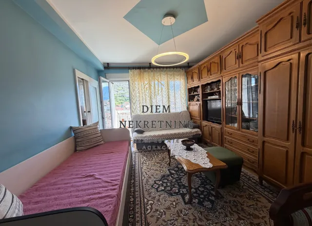 Living room with a sofa, large wooden wardrobe, and access to the terrace.