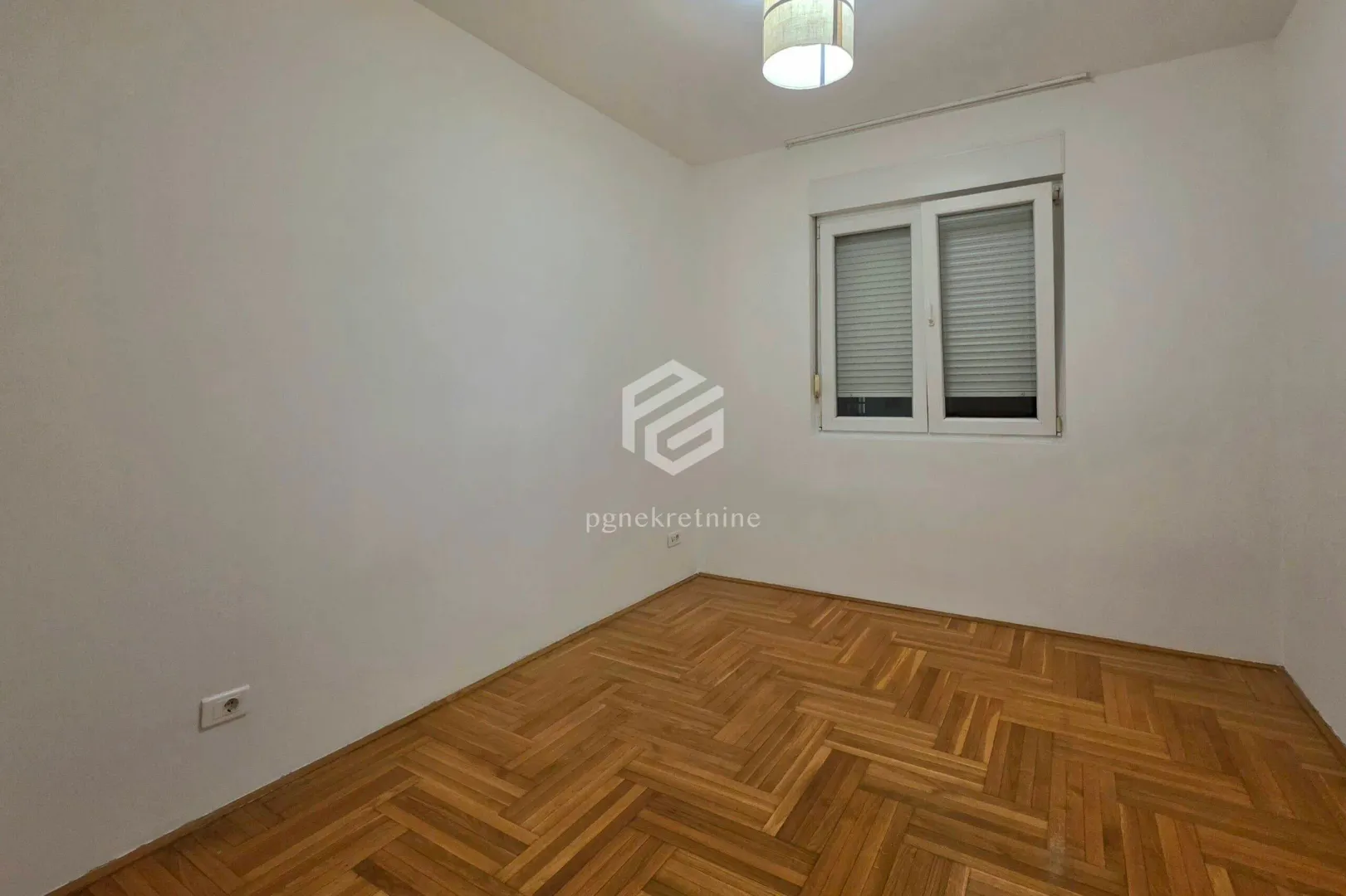 Empty room with parquet flooring and white walls.