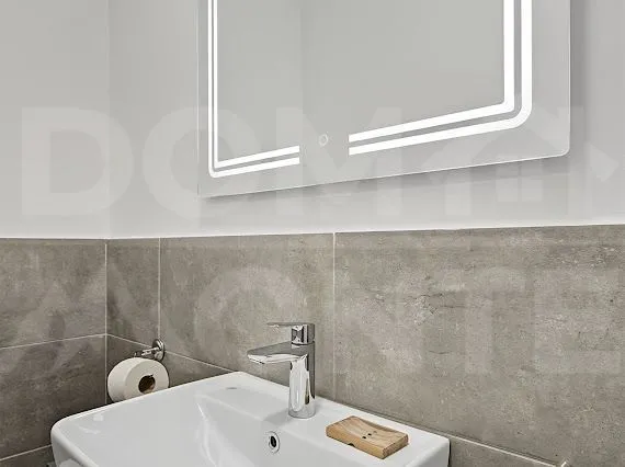 Close-up view of the washbasin with a faucet and mirror in the bathroom.