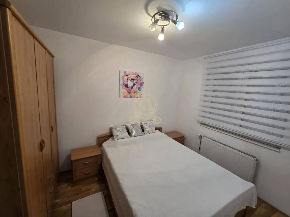 Nameštena spavaća soba sa bračnim krevetom, ormanom i prozorom.