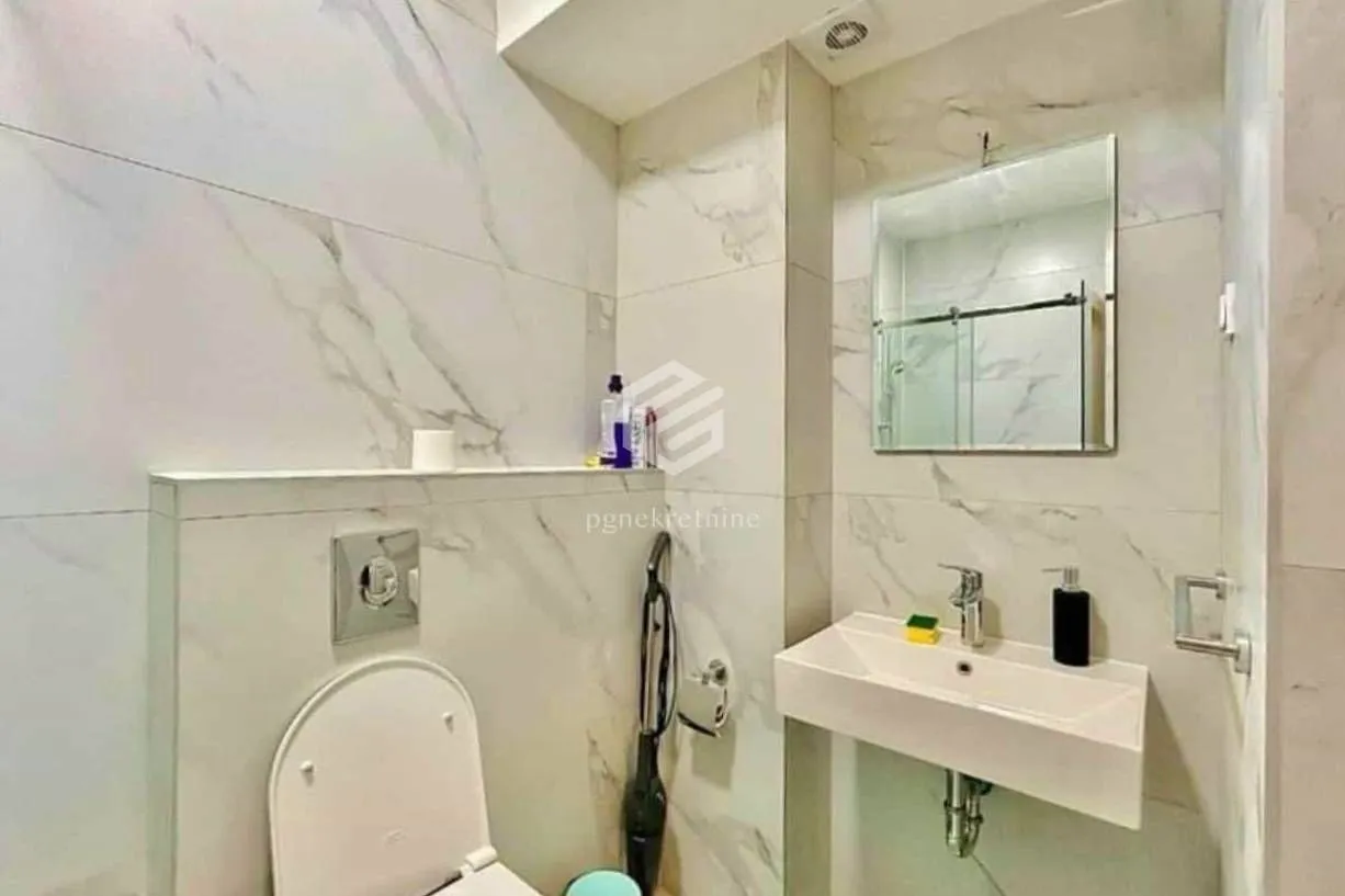 Modern bathroom tiled with marble-look tiles featuring a sink and a toilet.