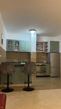 Kitchen with light green cabinets, a bar counter, and two bar stools. - image 5