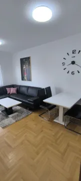 Bright living room with a black corner sofa and a dining table. - image 23