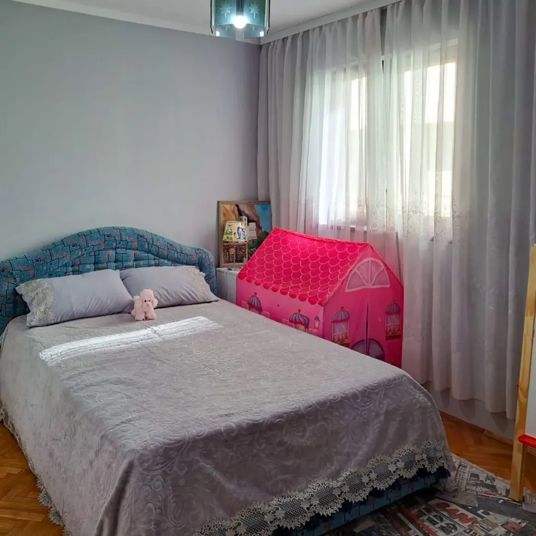 Spavaća soba sa bračnim krevetom i dječijim šatorom za igru pored prozora.