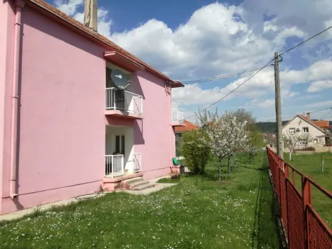 Vanjski izgled roze kuće sa dvorištem i zelenom travom. - image 2
