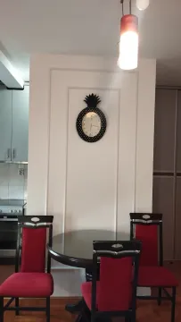 Trpezarija sa okruglim stolom, crvenim stolicama i zidnim satom. - image 3