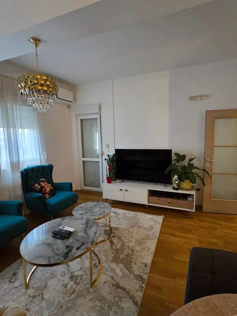 Uređena dnevna soba sa garniturom, stočićem i televizorom.