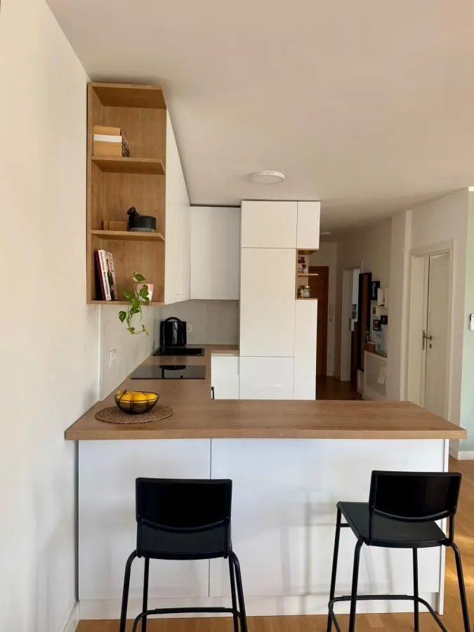 Moderna kuhinja sa šankom i drvenim detaljima.