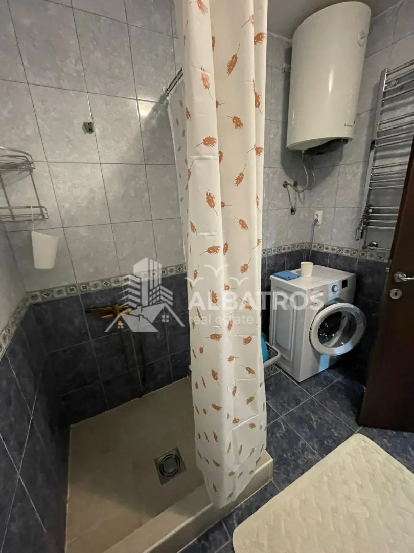 Bathroom equipped with a shower cabin, tiles, and a washing machine.