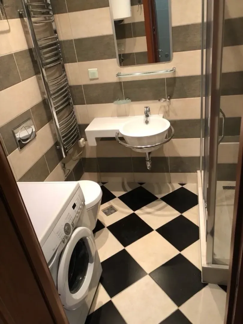 Small bathroom with a shower cabin, washbasin, and washing machine.