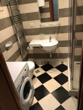 Small bathroom with a shower cabin, washbasin, and washing machine. - image 5