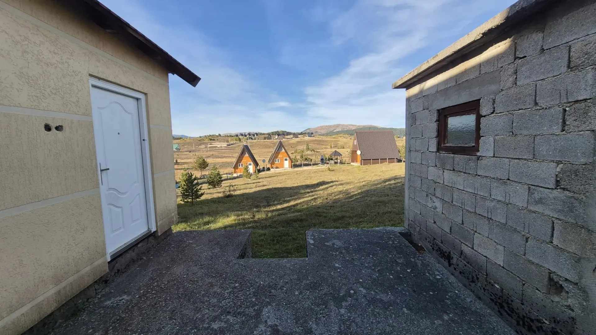 Pogled iz dvorišta na okolne objekte i prirodu.