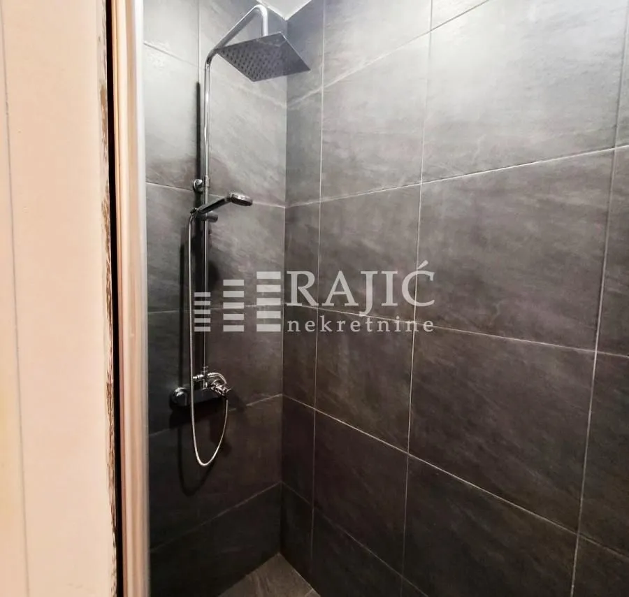 Modern shower enclosure tiled with dark tiles.