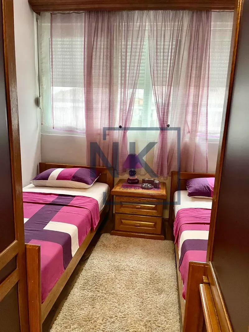 Bedroom with two single beds and a window with curtains.