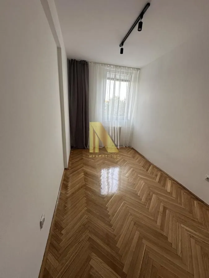 Prazna soba sa parketom i prozorom.