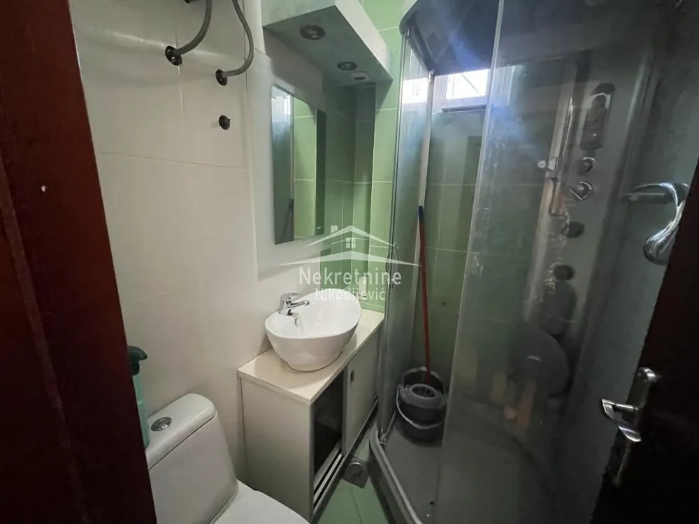Smaller bathroom with a washbasin, toilet, and shower cabin.