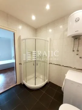 Smaller bathroom with a shower cabin, water heater, and ceramic tiles. - image 12