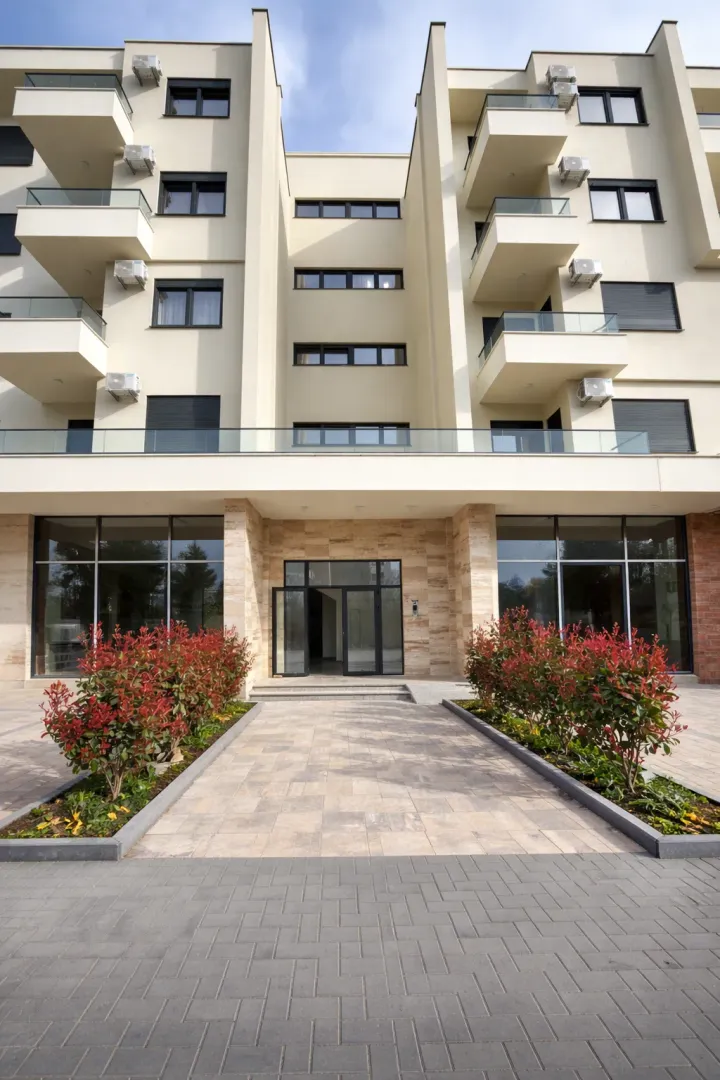 Main entrance and facade of a modern residential building with a landscaped yard.