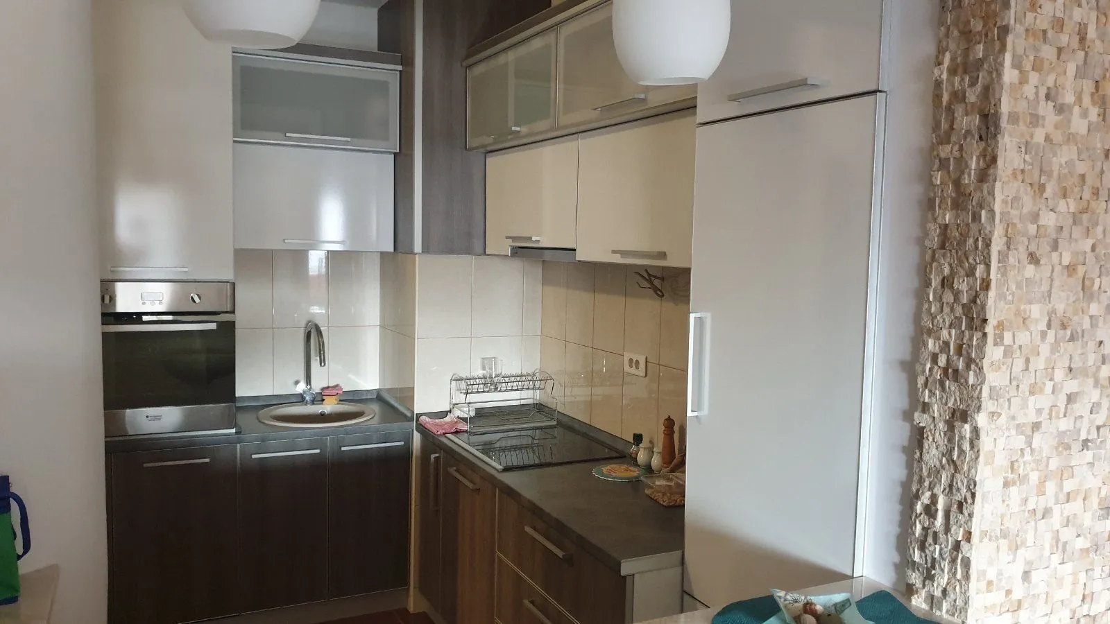 Svijetla kuhinja sa ugradnim aparatima i ukrasnim kamenim zidom.