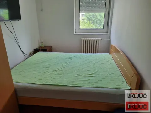 Spavaća soba sa bračnim krevetom, prozorom i zidnim televizorom. - image 3