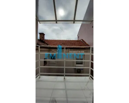 Covered balcony with white railing and a view of neighboring rooftops. - image 14