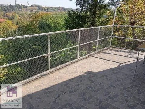Terasa sa popločanim podom i ogradom od žičane mreže sa pogledom na zelenilo. - image 12