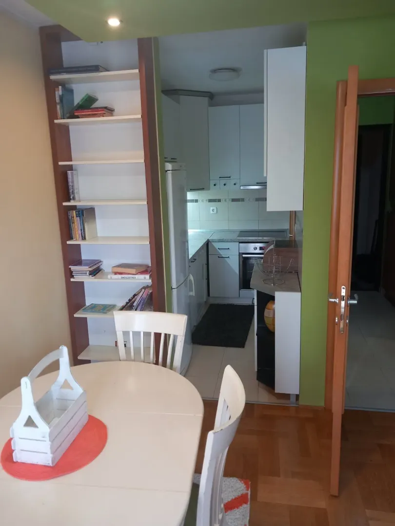 Pogled na funkcionalnu kuhinju sa trpezarijskim stolom u prvom planu.